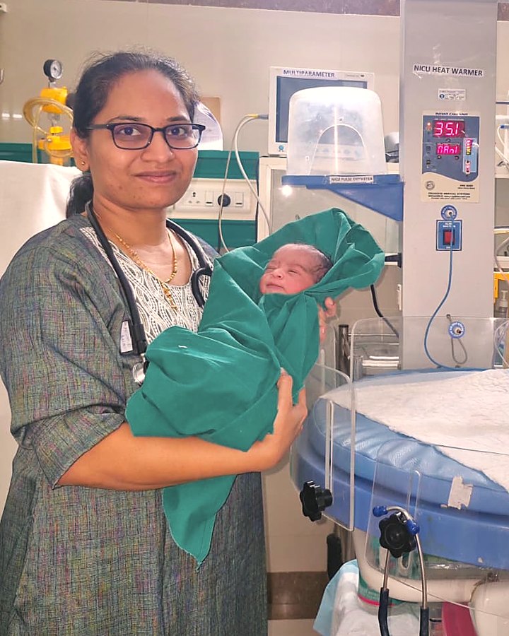 Dr. Megha Kadam holding a newborn beside a NICU heat warmer